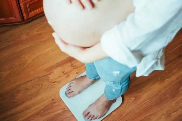 Image of woman weighing herself and experiencing weight gain through pregnancy Mickleover